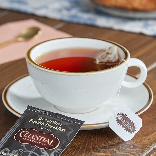 A cup of Celestial Seasonings Devonshire English Breakfast tea on a saucer with a tea bag.