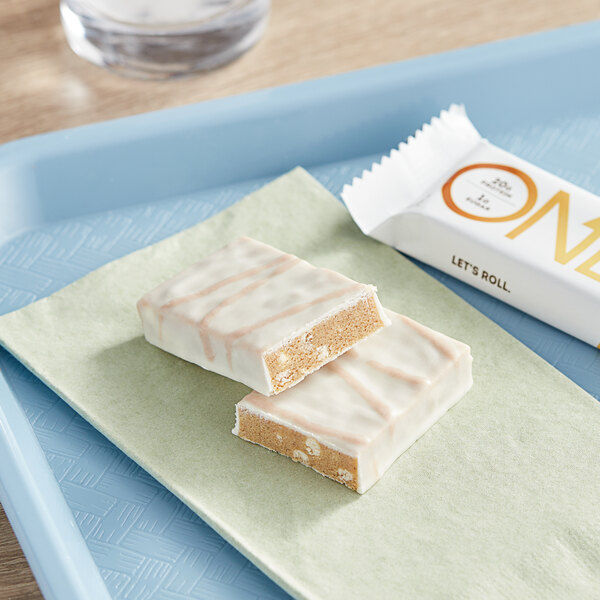 A ONE Cinnamon Roll protein bar on a blue tray.