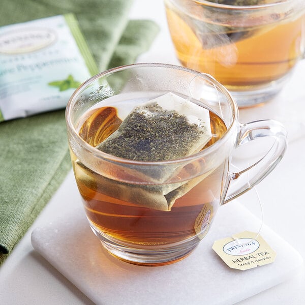 A glass cup of Twinings Pure Peppermint Herbal Tea with a tea bag in it.