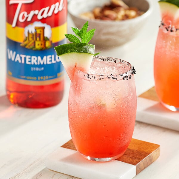 A glass of watermelon and cucumber margarita made with Torani Watermelon syrup with a slice of watermelon on the rim.