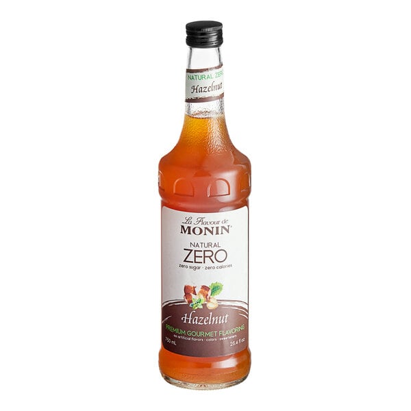 A bottle of Monin zero calorie hazelnut flavoring syrup with a white label and brown liquid.