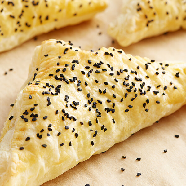 A close up of a croissant with black caraway seeds on top.