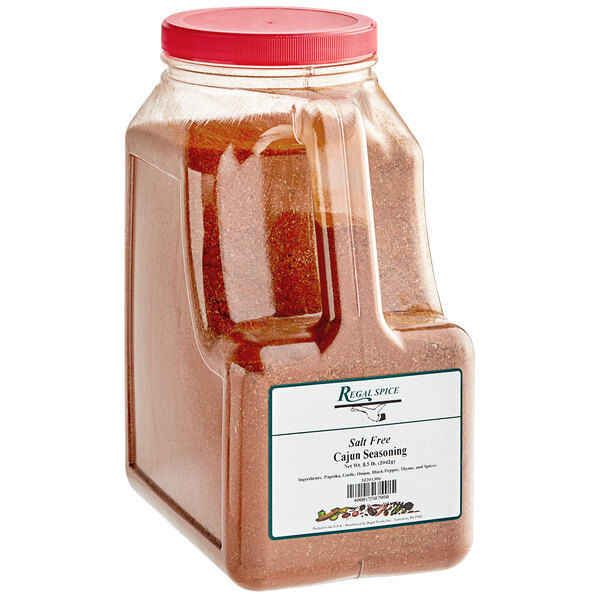 A large plastic container of Regal Salt-Free Cajun Seasoning with a red label.