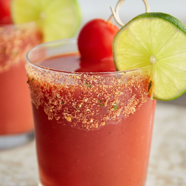 A glass of a Bloody Mary cocktail rimmed with Rokz salt and garnished with a lime and tomato.