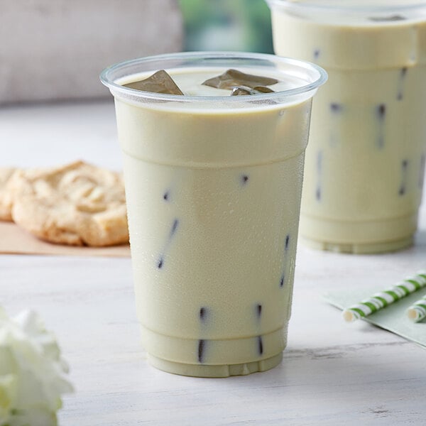 A plastic cup with white liquid and a straw.