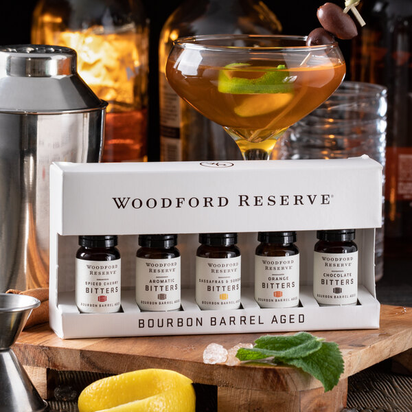 A Woodford Reserve Five-Pack of Bourbon Barrel Aged Bitters on a table with a martini glass.