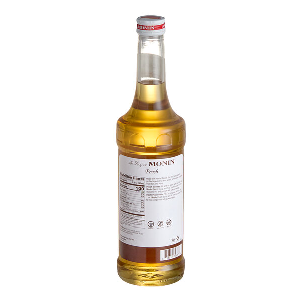 A bottle of Monin peach syrup with a white label.