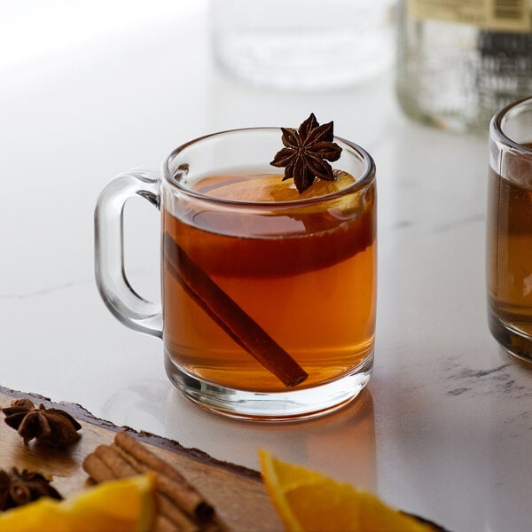 Two glass mugs of hot tea with Monin honey sweetener on a table.