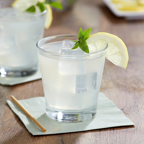 A glass of lemonade with ice and a lemon wedge.