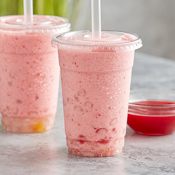 Two plastic cups with straws filled with pink strawberry smoothies.