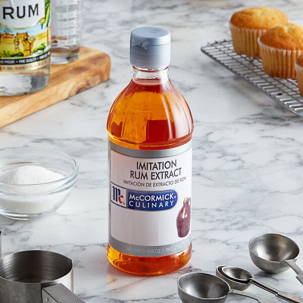 A bottle of McCormick Culinary Imitation Rum Extract on a table next to a variety of cupcakes.