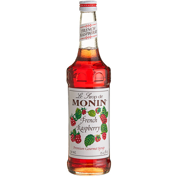 A close up of a bottle of Monin raspberry syrup with red liquid inside.