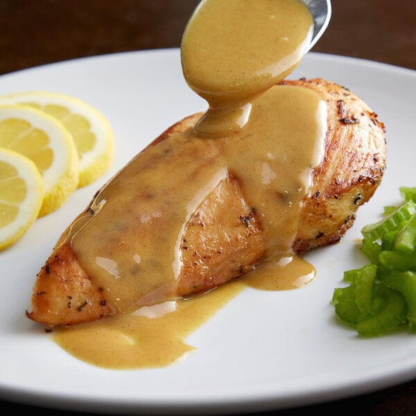 A plate of food with Regal yellow mustard sauce over a piece of meat.