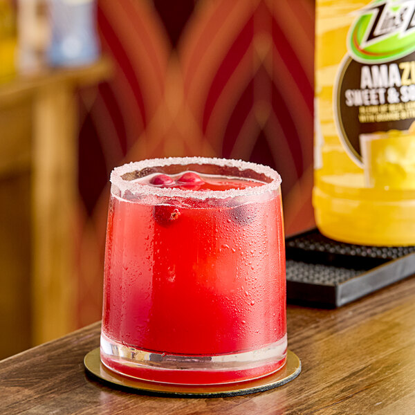 A glass of Zing Zang Sweet and Sour Mix with a red cocktail and berries.