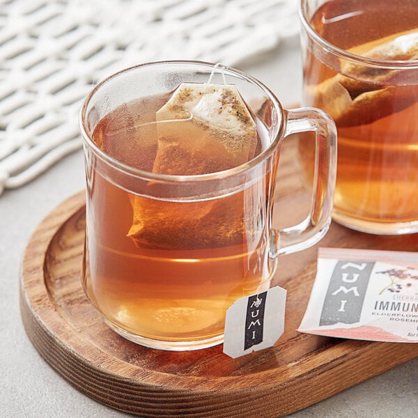 A glass mug of Numi Organic Immune Support Herbal Tea with a tea bag in it.