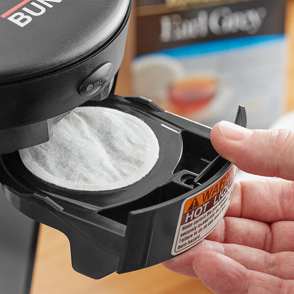 A hand holding a box of Bigelow Earl Grey tea single serve pods.