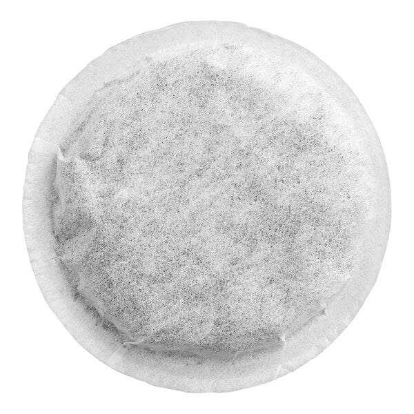 A round, flat, white mesh pod filled with a dark, granular substance, likely tea leaves, viewed from above.