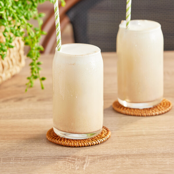 Two glasses of David Rio Tortoise Green Tea Chai Latte with straws on a table.