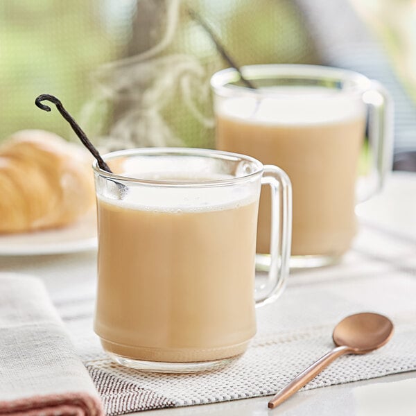 A glass mug of David Rio Flamingo Vanilla Decaf Sugar-Free Chai Tea Latte with a spoon on a table.