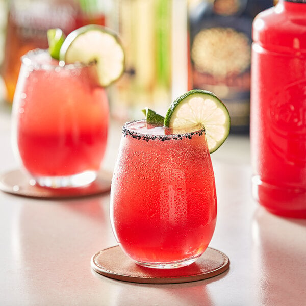 A glass of Finest Call Prickly Pear Syrup with a lime garnish on the rim.