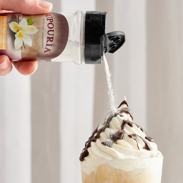 A hand pouring UPOURIA French Vanilla coffee topping onto a cup of whipped cream.