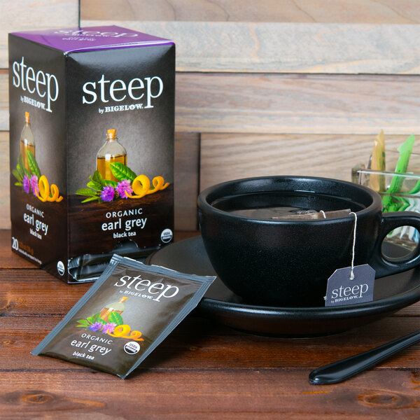 A cup of water with a Steep By Bigelow Earl Grey tea bag next to a box of Steep By Bigelow tea.