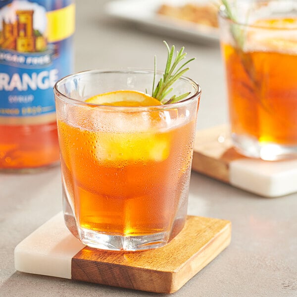 A glass of Torani sugar-free orange drink with a slice of lemon and rosemary.