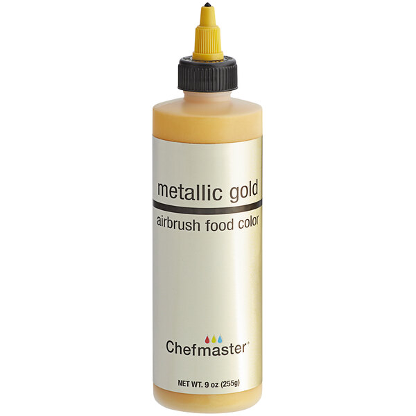 A close up of a Chefmaster Metallic Gold airbrush color bottle with a yellow cap.
