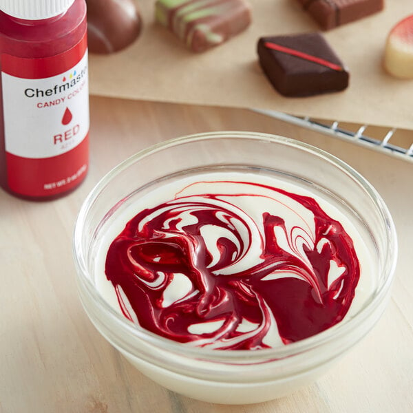 A bowl of red and white liquid with a spoon, colored red by Chefmaster Red Oil-Based Candy Color.