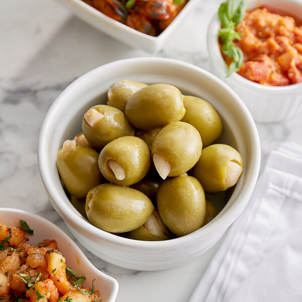 A white marble hotel buffet table with bowls of Belosa garlic stuffed green olives and other food.