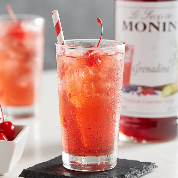 A glass of Monin grenadine mixed with a straw in it.