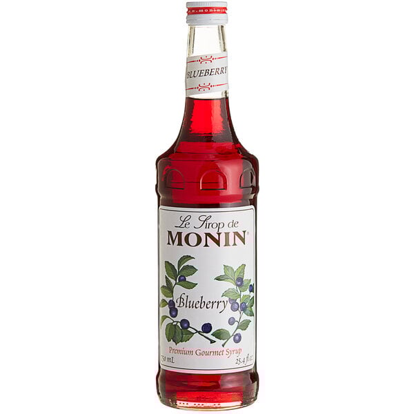 A close up of a Monin Blueberry Syrup bottle filled with red liquid.