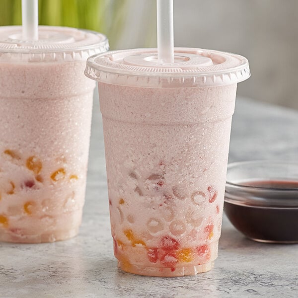 Two cups of pink grape bubble tea with straws on a counter.