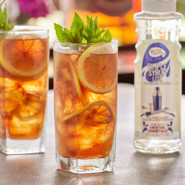 A group of glasses of ice tea with lemons and mint leaves on a white background.