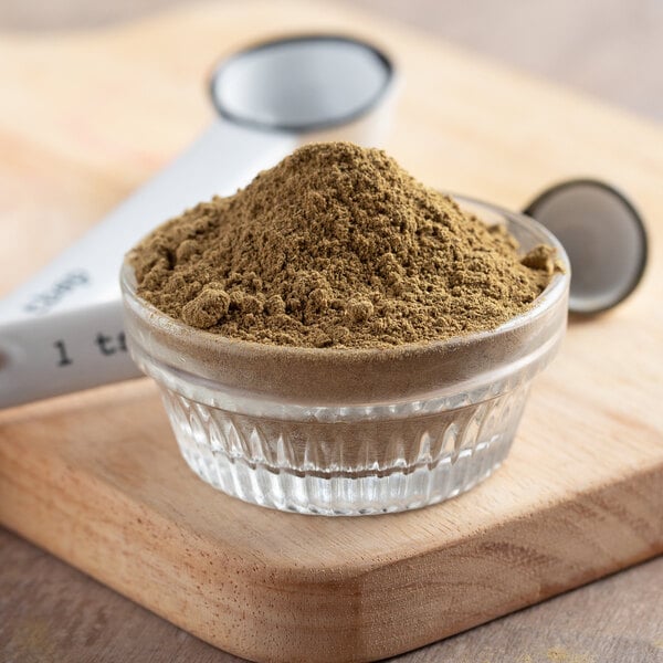 A bowl of Regal ground cumin powder on a cutting board.