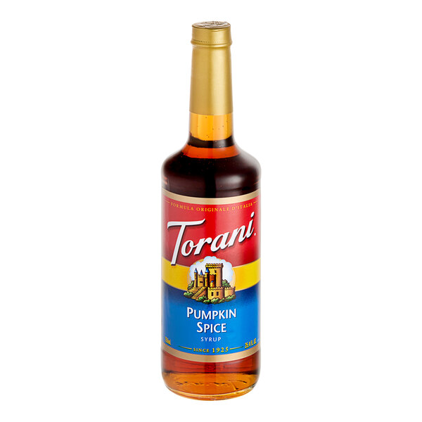 A Torani Pumpkin Spice flavoring syrup 750 mL glass bottle on a table with a label.