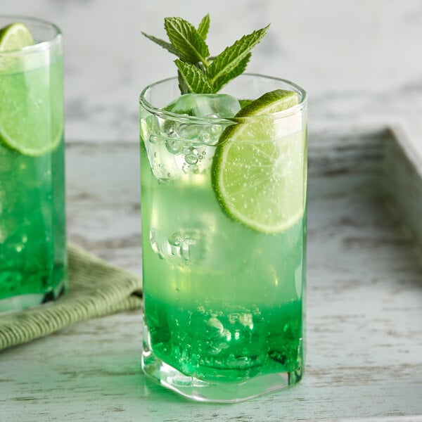 A glass of green drink with DaVinci Gourmet Sugar Free Lime Flavoring and lime slices.