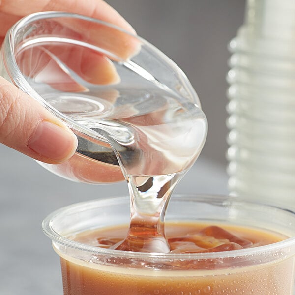 A hand pouring Bossen Liquid Fructose Syrup into a glass.