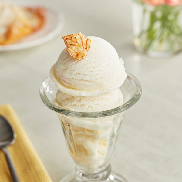 A glass cup with a scoop of Lloyd's of Pennsylvania cheesecake ice cream on top.