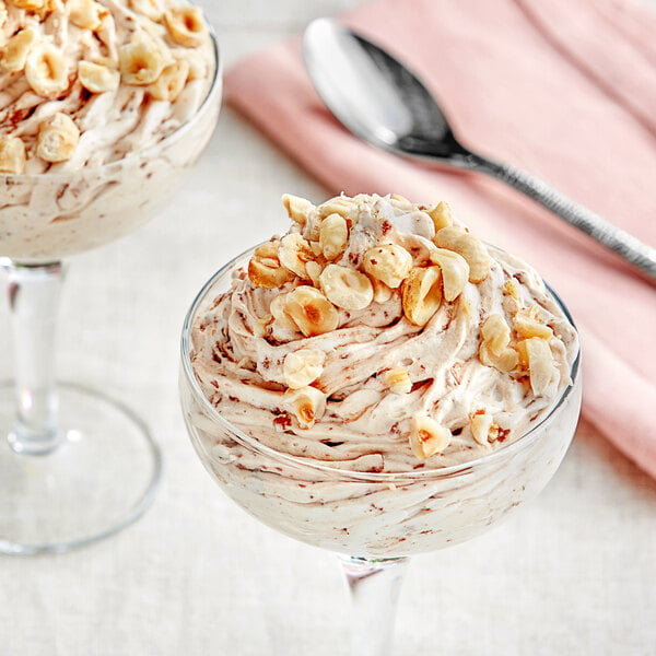 A glass of dessert with Cacao Barry Praline Feuilletine filling and nuts.