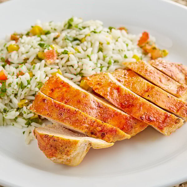 A plate of chicken and rice with Goya Sazon seasoning packets on a wood table.