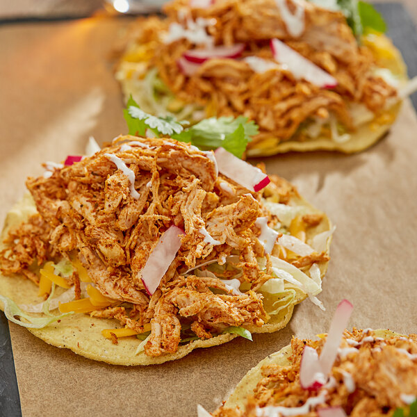 A table with three tacos on paper plates with Regal Salt-Free Taco Seasoning.
