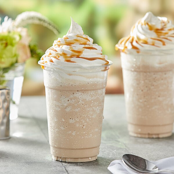 A glass of Capora Caramel Latte Frappe with whipped cream and caramel sauce.