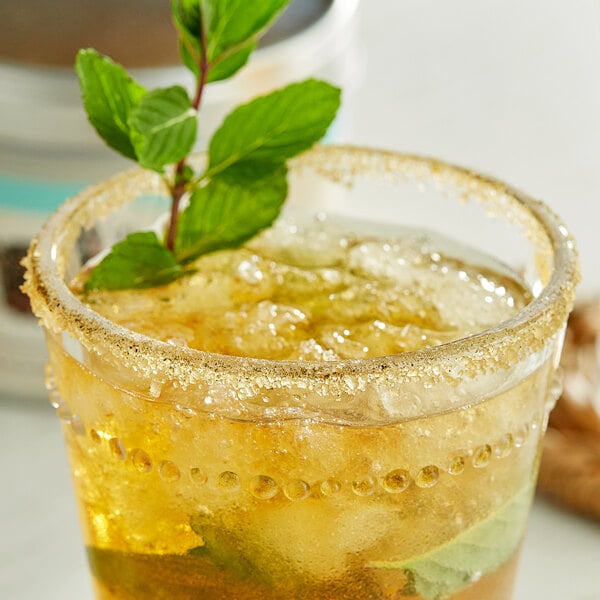 A glass with a drink and a Mint Julep Sugar garnished mint leaf.