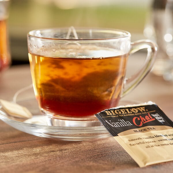 A cup of Bigelow Vanilla Chai tea on a saucer with a packet of tea.