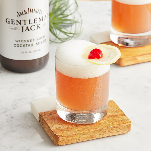 A glass of Jack Daniel's Whiskey Sour with a cherry on a coaster.