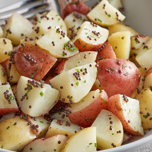 A bowl of potato wedges with Regal brown mustard seeds and green and red specks.