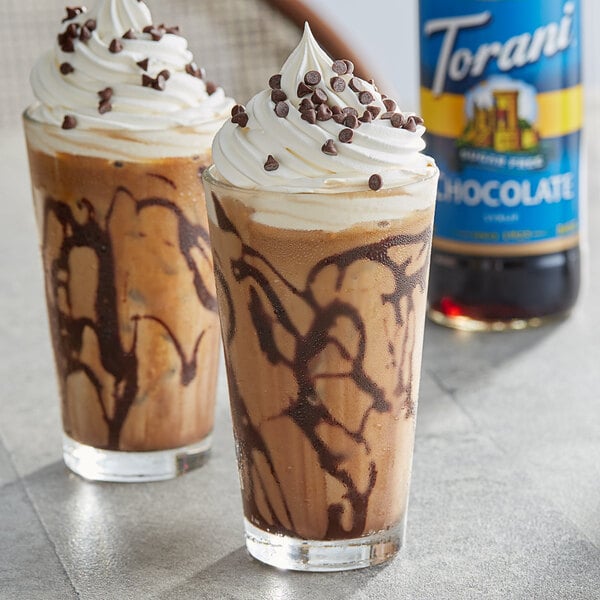 Two glasses of iced coffee with Torani sugar-free chocolate syrup and whipped cream on top.