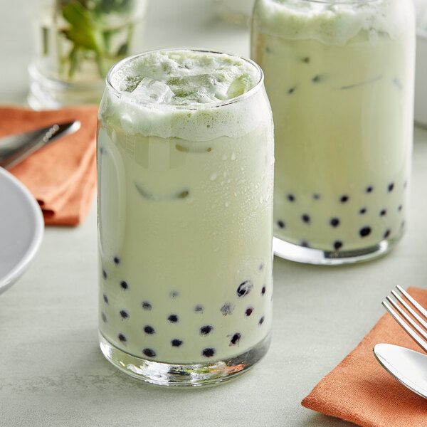 A glass of green Thai tea with black bubbles and a mint leaf.