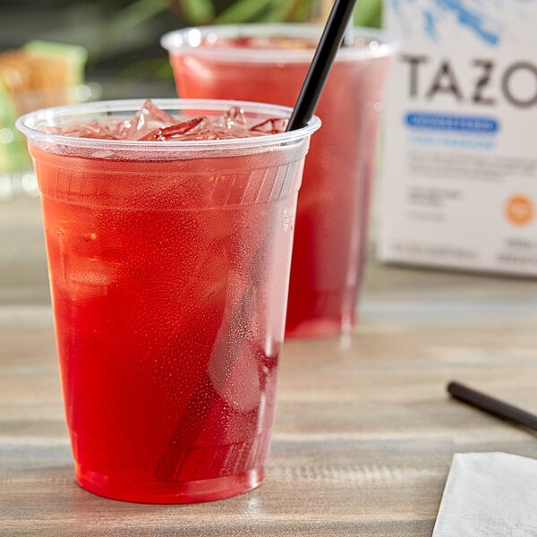 A plastic cup of Tazo Iced Passion Tea with a red liquid and ice with a black straw.